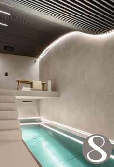 an indoor swimming pool with stairs leading up to the upper floor and above it is a white staircase