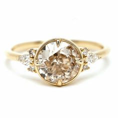 a yellow gold ring with an oval cut diamond surrounded by three smaller round brilliant diamonds