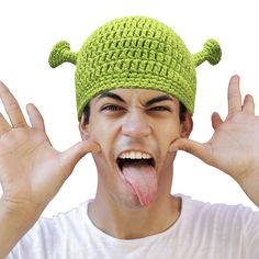 a man with his tongue sticking out and wearing a green knitted hat on top of his head