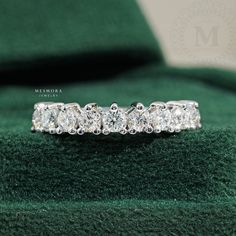 a diamond ring sitting on top of a green velvet cushion