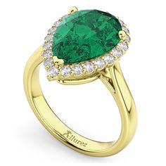 a pear shaped emerald and diamond ring in yellow gold with diamonds around the shans