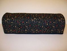 a black and red flowered bag sitting on top of a white table next to a wall