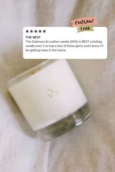 a white candle sitting on top of a bed next to a tag that says the best