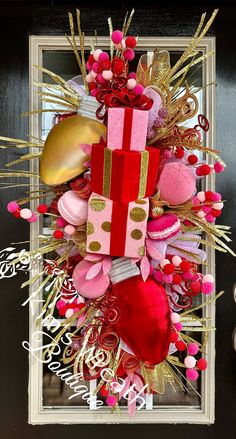 a christmas wreath with pink, red and gold decorations on it's front door