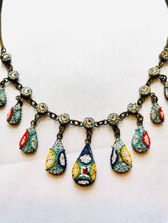 "Although the Italians are still making and selling souvenir mosaics, this necklace is a lot older at about 70-80 years old. Nine drops rivière with the largest in the center. Brass chain and drop cases. One tiny tesserae is missing on one ball. Very tiny and not noticeable. Closes with the original thumb spring clasp and is 16\" in length." Antique Handmade Teardrop Necklace, Vintage Teardrop Collectible Jewelry, Vintage Multicolor Pendant Necklaces, Vintage Multicolor Teardrop Jewelry, Vintage Handmade Teardrop Pendant Necklace, Antique Dangle Necklaces For Jewelry Making, Vintage Multicolor Jeweled Necklaces, Antique Jeweled Collectible Necklace, Collectible Vintage Teardrop Necklace