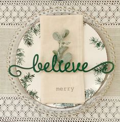 a plate that has a napkin on it with the word believe written in green lettering