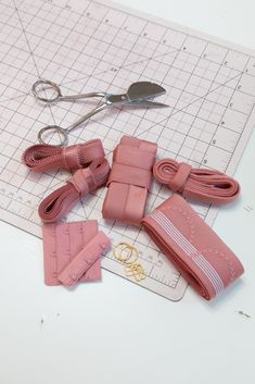 several pieces of pink leather sitting on top of a cutting board next to scissors and other items