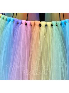 several different colored tulle skirts hanging on a line with black pins in the middle