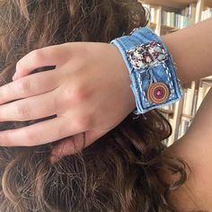 a woman wearing a blue jean bracelet with an elephant on it's side and a red bead around the wrist