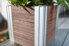 a wooden planter with green plants in it on top of a wood decking area