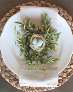 a white plate topped with a bird's nest on top of a woven napkin