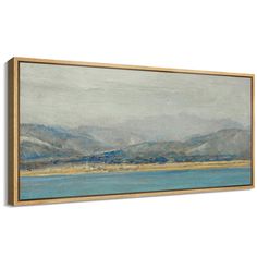 a painting hanging on the wall above a blue body of water with mountains in the background