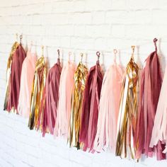 pink and gold tassels hanging on a white brick wall