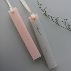 two pink tubes sitting next to each other on top of a gray surface with flowers in the background