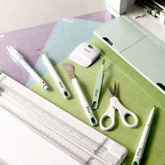 scissors, rulers and other office supplies are on a cutting board next to a cricut machine