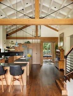 an open concept kitchen and dining area with wood flooring, white walls and beams