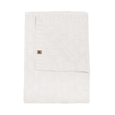 the white blanket is folded up on a white surface and has a brown patch in the middle