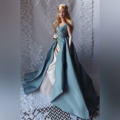 a barbie doll wearing a blue gown and flower in her hand on a white background