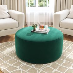 a living room with two white couches and a green ottoman in front of a window