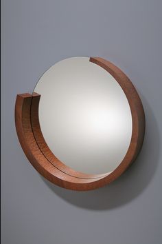 a round mirror mounted on the wall with a wooden frame and wood trim around it