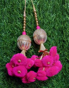 two pink flowers are hanging from some gold earring hooks on the green grass,