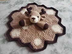 a crocheted teddy bear sitting on top of a rug