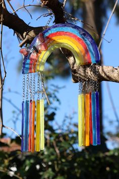 a rainbow colored wind chime hanging from a tree