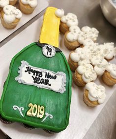 a green bottle cake sitting on top of a table next to cupcakes