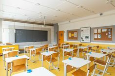 an empty classroom with desks and chairs in front of a chalkboard on the wall