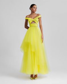 a woman in a yellow dress is standing with her hands on her hips and looking off to the side