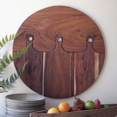 a wooden cutting board sitting on top of a table next to plates and bowls filled with fruit