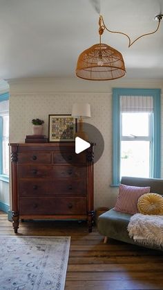 a living room filled with furniture and a wooden dresser in front of a large window