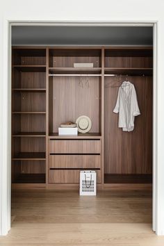 a closet with wooden shelves and clothes hanging on the wall next to an open door