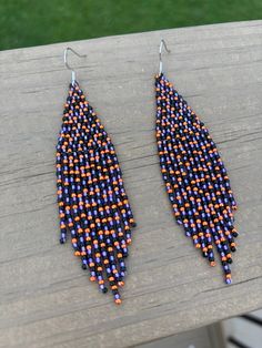 two pairs of beaded earrings sitting on top of a wooden table