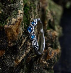 Handcrafted from sterling silver, our Elvish Forest Fantasy Wedding Ring is an enchanting and unique piece that captures the essence of nature's magic. With intricate details of branches and leaves surrounding an aquamarine, this witch engagement ring is perfect for those seeking a mystical and witchy aesthetic. Ideal as a nature jewelry gift, the design reflects the core of the forest and the whimsy of fantasy. Characteristics: Metal - Recycled solid sterling silver  Stone - Cubic Zirconia Fini Fantasy Wedding Rings Silver, Elven Engagement Ring, Forest Fantasy Wedding, Witch Engagement Ring, Witchy Engagement Ring, Fantasy Rings Magic, 1950 Outfits, Fantasy Wedding Rings, Elf Ring