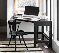 a desk with a laptop on it in front of a window and a chair next to it