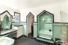 a bathroom with green and black tiles on the walls, two sinks and a bathtub