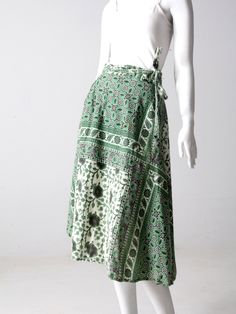 "This is a 1970s vintage wrap skirt. The all cotton skirt features a green, black and cream block floral print. It wraps closed with long ties and belt loops. A rare style with pockets at the waist! CONDITION In good condition with wear consistent with age and use. APPPROXIMATE FIT: S/M MEASUREMENTS Fits Waist Best: 26\" - 30\" .. 33 cm - 76.2 cm Waistband open: 35.5\" ... 90.2 cm Ties each: 27\" ... 68.6 cm Length: 29\" ... 73.7 cm HOW WE MEASURE * Skirt measured lying flat * Waistband open mea Bohemian Green Long Wrap Skirt, Green Bohemian Long Wrap Skirt, Green Bohemian Wrap Skirt For Spring, Green Vintage Long Skirt, Vintage Green Long Skirt, Retro Green Long Skirt, Vintage Long Green Skirt, Retro Green Long Skirt Bottoms, Green Cotton Wrap Skirt For Spring