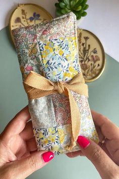 a woman holding up a wrapped gift box with a bow on the front and side