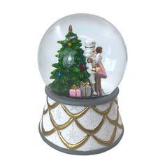 a snow globe with a christmas tree in it and a man kissing a woman on the cheek