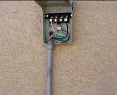 an electrical box attached to the side of a building with wires and plugs in it