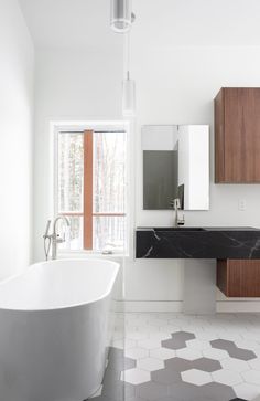 a white bath tub sitting in a bathroom next to a window