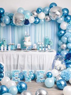 a blue and silver balloon arch with the word eve on it in front of a cake