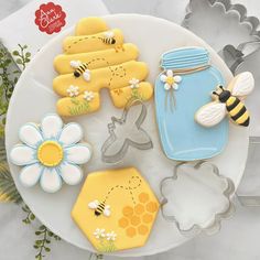 decorated cookies and cookie cutters on a plate with flowers, bees and honeycombs