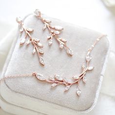 a close up of a piece of jewelry on a white cloth with flowers and leaves