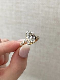 a person holding a ring with a diamond in it's middle and two diamonds on the other side