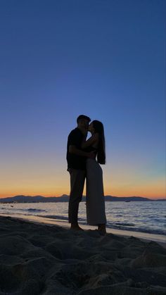 a couple kissing on the beach at sunset