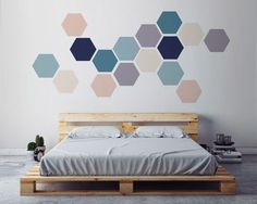 a bed sitting in front of a white wall with hexagonal shapes on it