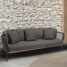 a couch sitting in front of a stone wall next to a rug on the floor