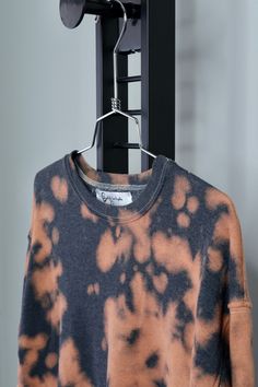 an orange and black tie dye shirt hanging on a rack